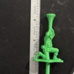 Green toy soldier golf tee next to a metal ruler to show its height