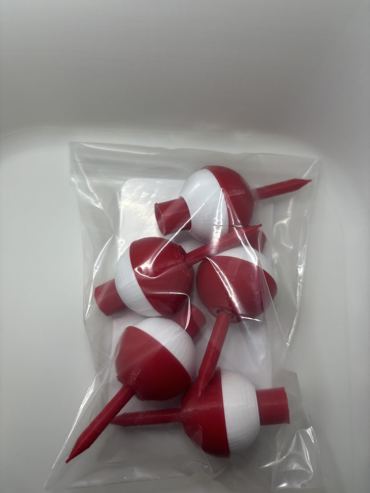 Five red and white bobber golf tees inside a clear bag