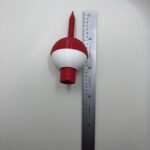 Red and white bobber golf tee next to a metal ruler to show its length