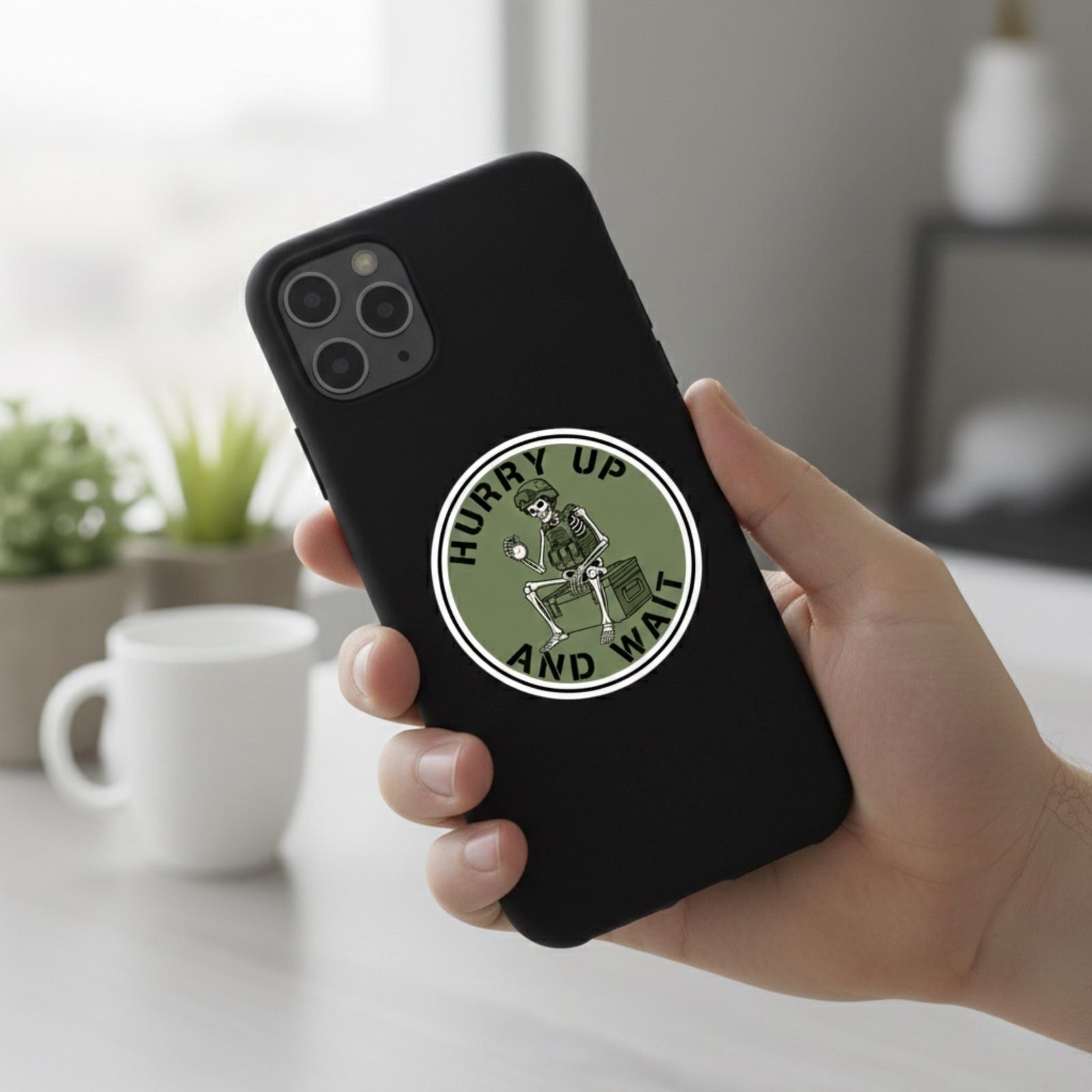 Hurry Up and Wait sticker on a black phone case held in a hand