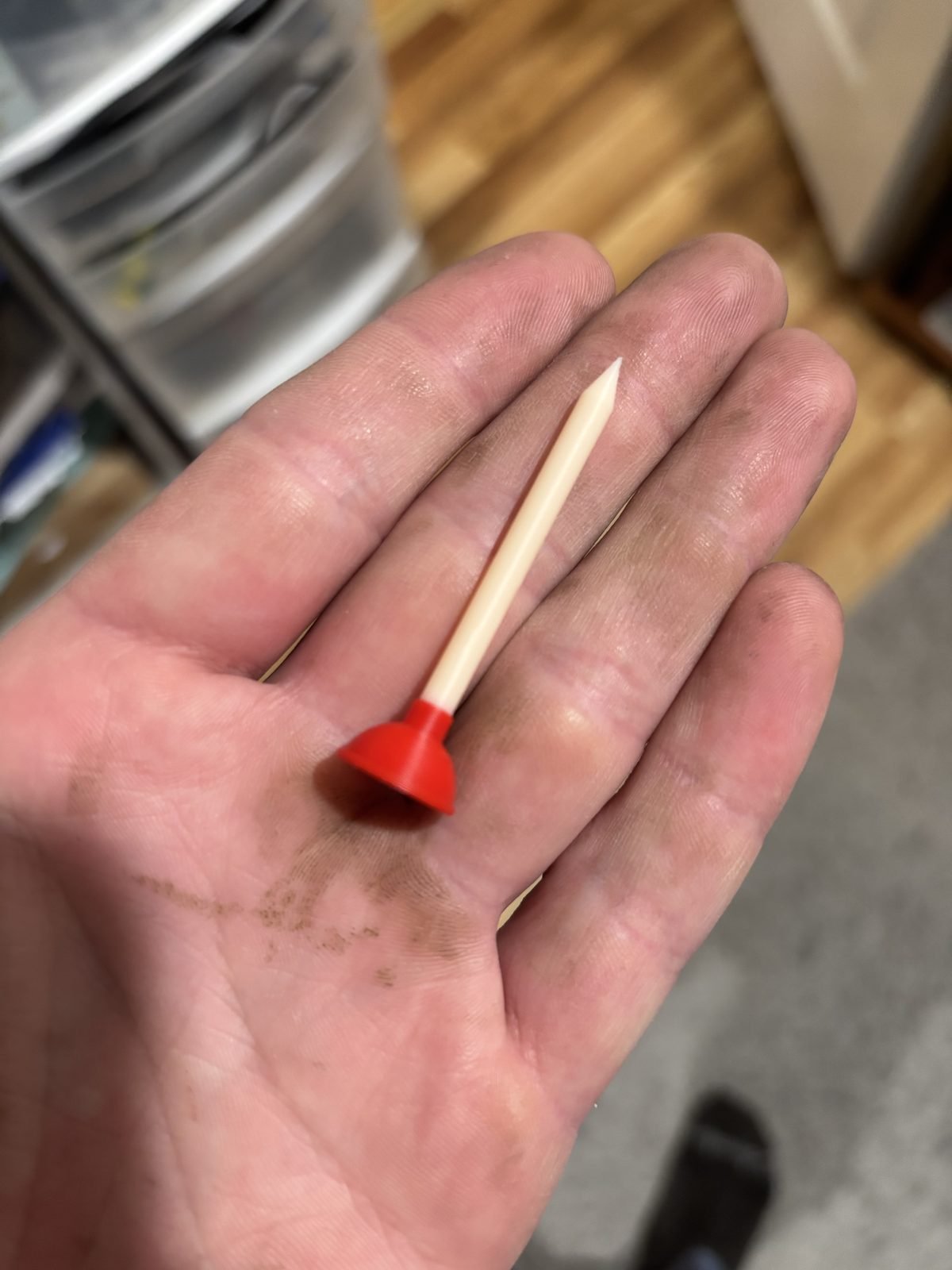 Golf tee with a red plunger cup lying in an open palm