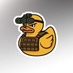 Die-cut sticker of a yellow rubber duck wearing four-tube night vision goggles and a brown plate carrier