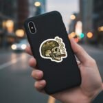 Tactical skull sticker on a black phone case held in a hand on a city street